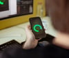 Auf dem Bild sieht man einen Mann von hinten sitzend an einem Schreibtisch vor einem Bildschirm. Er hat ein Smartphone in der Hand, auf dem die Driver Scoring App von prodot zu sehen ist.