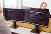 Zwei Mitarbeiter von prodot arbeiten im Büro vor Monitoren mit Code