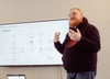 A colleague from prodot stands in front of a screen and gesticulates