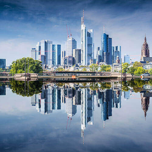 Ein Bild von Hochhäusern vor einer Uferlinie mit Wasser.